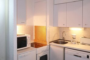 A compact kitchen with a microwave, coffee maker, sink, and dishwasher.