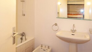 Ein Badezimmer mit Badewanne, Waschbecken und einem spiegelübersichtigen Schminkspiegel mit Beleuchtung.