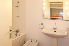 Ein Badezimmer mit Badewanne, Waschbecken und einem spiegelübersichtigen Schminkspiegel mit Beleuchtung.
