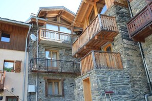 Un immeuble à plusieurs étages, doté de balcons en bois et de murs en pierre.
