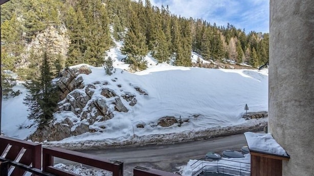 Montaña nevada con una terraza de madera y vista a una carretera.