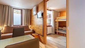 Una habitación acogedora con una pared de madera, un sofá, una mesa y una cama litera.
