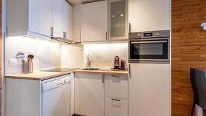 Una cocina moderna con armarios blancos, horno empotrado y lavavajillas.