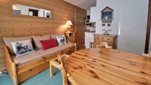 A wooden cabin interior with a sofa, a dining table, and a kitchen area. - 10m from ski slopes, 33m², Méribel-Mottaret (Méribel - Les Allues)