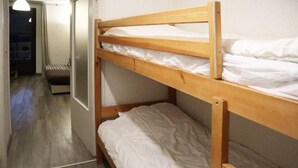 A bunk bed with white bedding in a room with a wooden floor and a door leading to another room. - Ski-in/ski-out & foot of the slopes, 7th floor, view valley, balcony, tv, 26m², Les Orres (Les Orres)