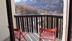 A balcony with two red chairs, a view of snow-capped mountains, and a forested valley. - Ski-in/ski-out & foot of the slopes, 7th floor, view valley, balcony, tv, 26m², Les Orres (Les Orres)