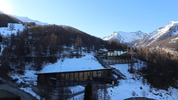 A modern building with large glass windows, surrounded by snow-covered mountains and trees. - Ski-in/ski-out & foot of the slopes, 7th floor, view valley, balcony, tv, 26m², Les Orres (Les Orres)