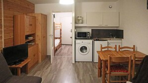 A compact living space with a television, wooden furniture, a washing machine, and a kitchenette. - Ski-in/ski-out & foot of the slopes, 7th floor, view valley, balcony, tv, 26m², Les Orres (Les Orres)