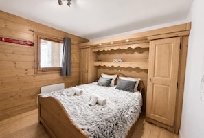 A wooden-paneled room with a bed, a window with curtains, a shelf with the word 'DREAM' on it, and a wardrobe. - 100m from ski slopes, 1st floor, terrace, parking, tv, 37m², Saint Martin de Belleville (Saint-Martin-de-Belleville)