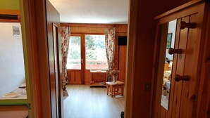 Ein Holzinnenraum mit Essbereich, einem kleinen Tisch mit einer Vase und Blick durch ein Fenster.