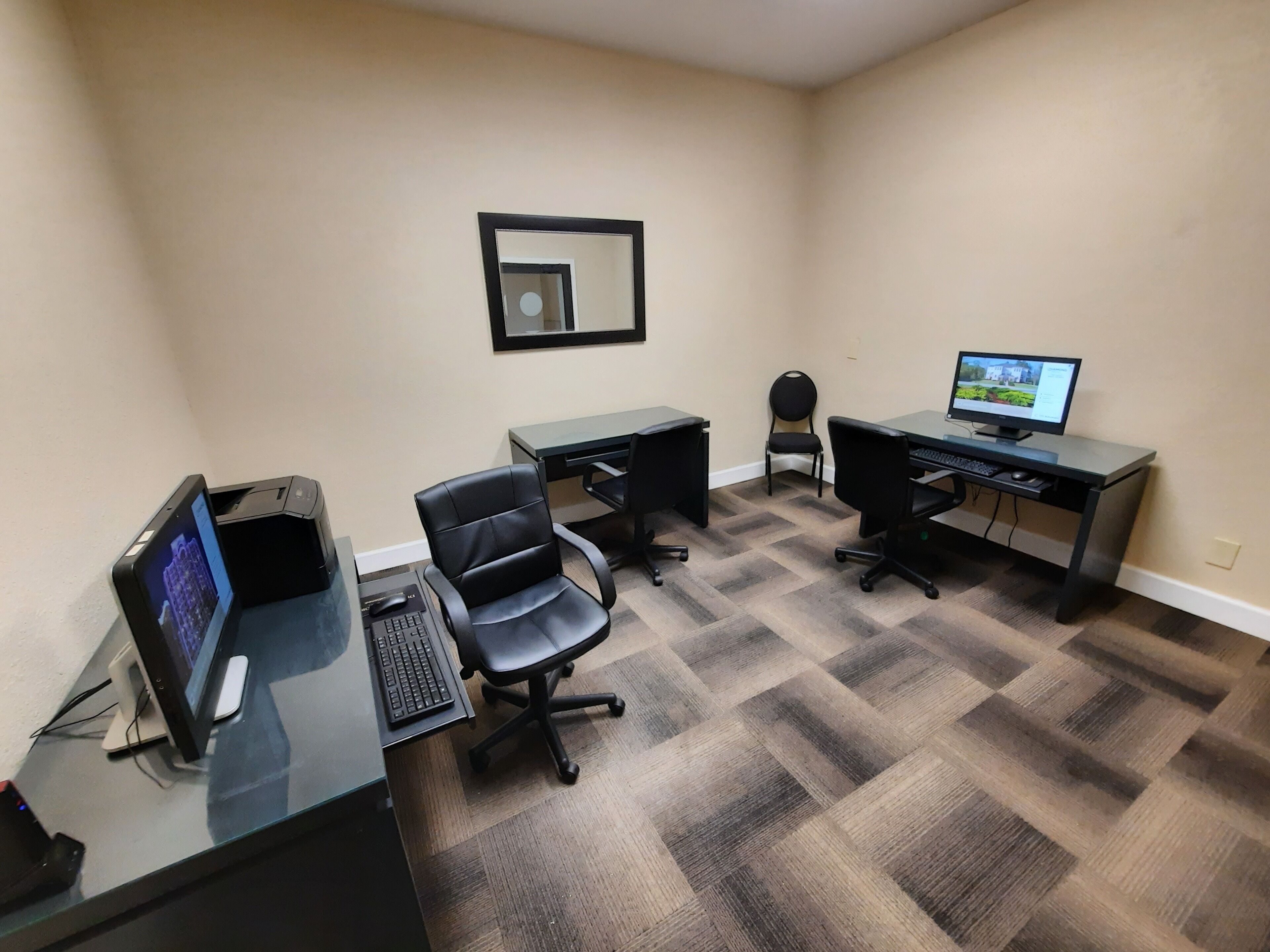 Un ufficio moderno con due scrivanie, due sedie e un monitor per computer.