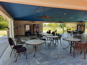 An outdoor covered patio area with tables and chairs, ceiling fans, and vending machines. - Romantic Getaway Walk-in Suite. Resort Amenities! Remodeled! Excellent Rates! (Branson)
