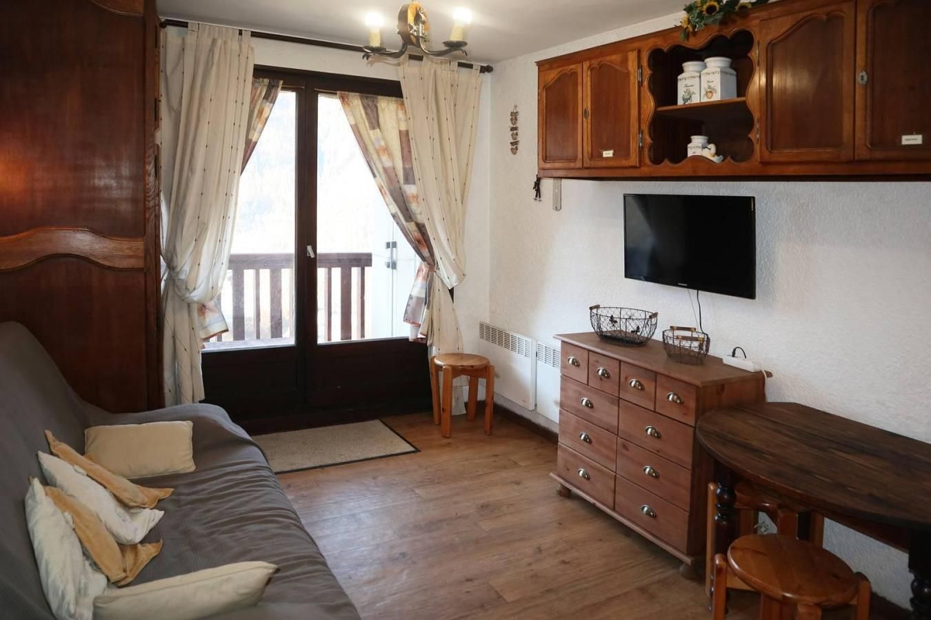 Een gezellige woonkamer met een bank, een houten kast en een televisie.