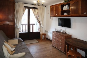 A cozy living room with a sofa, wooden cabinet, and a television.