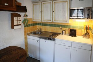 A compact kitchen with a sink, stove, and microwave.