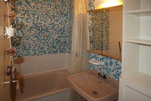 A bathroom with a bathtub, a sink, and a mirror.