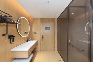 A modern bathroom with a white sink, a mirror with a light halo, a towel rack, and a glass shower enclosure. - Ji Hotel (Changzhou)