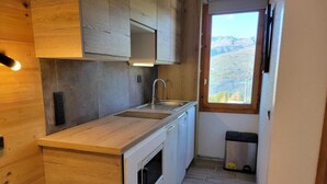 Eine kleine Küche mit Holzausstattung, einer Spüle und einem Fenster mit Blick ins Freie.