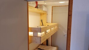 Ein kleiner, abgeschlossener Raum mit einem Etagenbett und einer Tür.