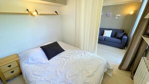 A bedroom with a bed, a nightstand, a sofa, and a wall-mounted shelf. - 10m from ski slopes, 2nd floor, view mountain, balcony, tv, ski locker, 26m², Les Menuires (Les Menuires)