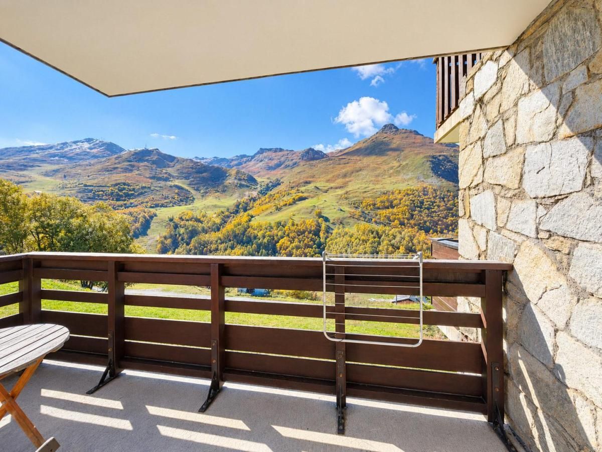 Un balcón con banco y mesa de madera, con vistas a un paisaje montañoso.