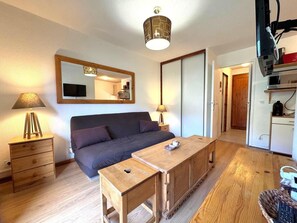 A cozy room with a bed, a wooden table, a lamp, and a mirror.