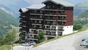 A multi-story hotel with balconies, set against a mountainous backdrop. - 10m from ski slopes, 1st floor, view ski slopes, balcony, tv, ski locker, 30m², Les Menuires (Les Menuires)