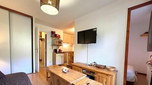 A compact room with a bed, a wooden desk, a television, and a kitchenette. - 10m from ski slopes, 1st floor, view ski slopes, balcony, tv, ski locker, 30m², Les Menuires (Les Menuires)
