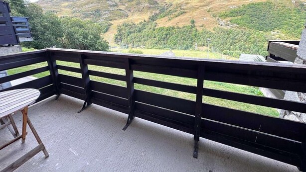 A balcony with a wooden table and chairs, overlooking a mountainous landscape. - 10m from ski slopes, 1st floor, view ski slopes, balcony, tv, ski locker, 30m², Les Menuires (Les Menuires)