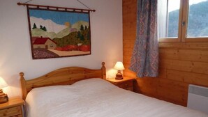 A wooden bed with a white mattress in a room with wooden walls and a window. - 1st floor, view village, terrace, tv, ski locker, 39m², Méribel (Les Allues)