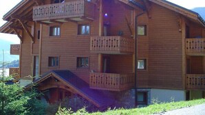 A multi-story wooden chalet with balconies, a chimney, and a sloped roof. - 1st floor, view village, terrace, tv, ski locker, 39m², Méribel (Les Allues)