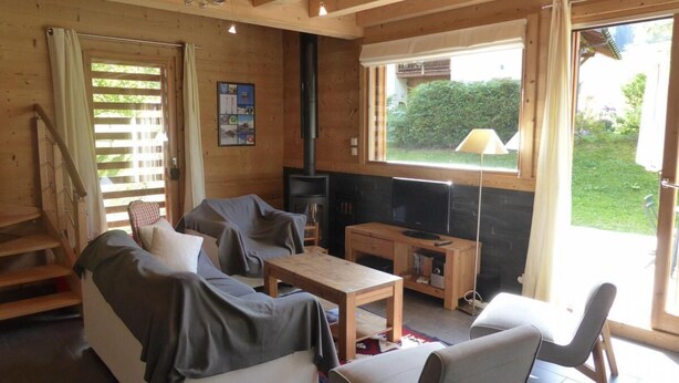 A cozy cabin interior with a sofa, a small table, a TV, and a fireplace.