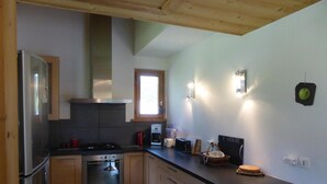 A modern kitchen with stainless steel appliances, wooden cabinets, and a black countertop.