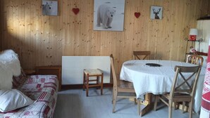 A cozy room with wooden walls, a white sofa, a dining table with chairs, and wall art of a polar bear and deer. - 200m from shops, Ground floor, balcony, tv, ski locker, 29m², Valloire (Valloire)