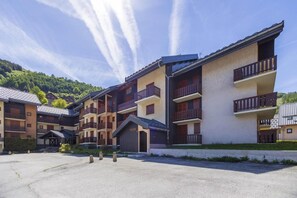 A multi-story hotel with balconies, a courtyard, and a mountainous backdrop.