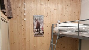 A small, wooden-paneled room with a bunk bed, a ladder, a small wooden stool, and a poster of a deer. - 200m from shops, Ground floor, balcony, tv, ski locker, 29m², Valloire (Valloire)
