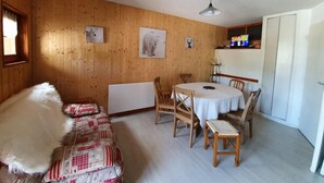 A cozy room with wooden walls, a round table with chairs, a bed with a white fluffy blanket, and a ceiling fan. - 200m from shops, Ground floor, balcony, tv, ski locker, 29m², Valloire (Valloire)