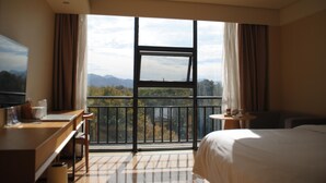 Een hotelkamer met een groot raam, een bed, een bureau en een stoel.