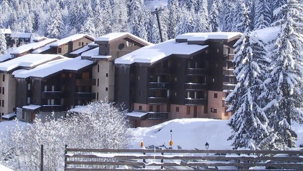 A snow-covered resort with multi-story buildings, a wooden fence, and a mountainous backdrop. - 26m from ski slopes, 4th floor, balcony, tv, ski locker, 35m², Valmorel (Valmorel)