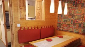 A wooden room with a table, benches, and a patterned wall. - 26m from ski slopes, 4th floor, balcony, tv, ski locker, 35m², Valmorel (Valmorel)