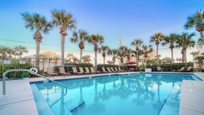 A swimming pool with lounge chairs and palm trees. - Boho Beach Vibes @ Caribbean Dunes,125 (Destin)