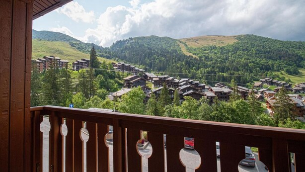 Uitzicht vanaf een balkon op een bergdorp met traditionele houten huizen en een heldere lucht.