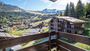 Een balkon met uitzicht op een bergdorp, met traditionele gebouwen en een heldere lucht.