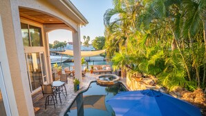 Un espace piscine agrémenté d’une terrasse, de sièges et de plantes tropicales.