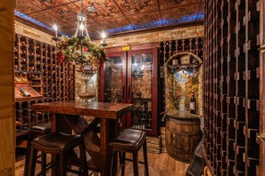 Enjoy a drink at the bar with a wine bottle and glass on the counter, surrounded by wooden accents and a chandelier.