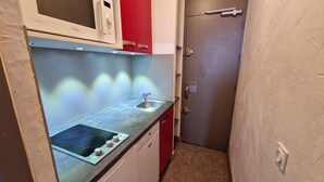 A compact kitchen with a microwave, sink, and red cabinets. - 10m from ski slopes, view ski slopes, balcony, tv, ski locker, 25m², La Plagne (La Plagne)
