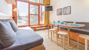 A cozy living area with a sofa, a dining table with stools, and a TV mounted on the wall. - 300m from resort center, 1st floor, view valley, balcony, tv, 37m², Les Arcs (Les Arcs)