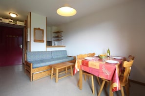 Een eetgedeelte met een houten tafel gedekt voor twee personen, een bank en een slaapbank.