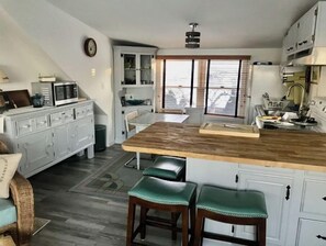 A kitchen with a wooden island, white cabinets, and a dining area with a bench.