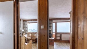 A wooden-framed room with a dining area, a television, and a view of a snowy landscape. - 20m from ski slopes, 5th floor, balcony, tv, ski locker, 50m², La Plagne (La Plagne)